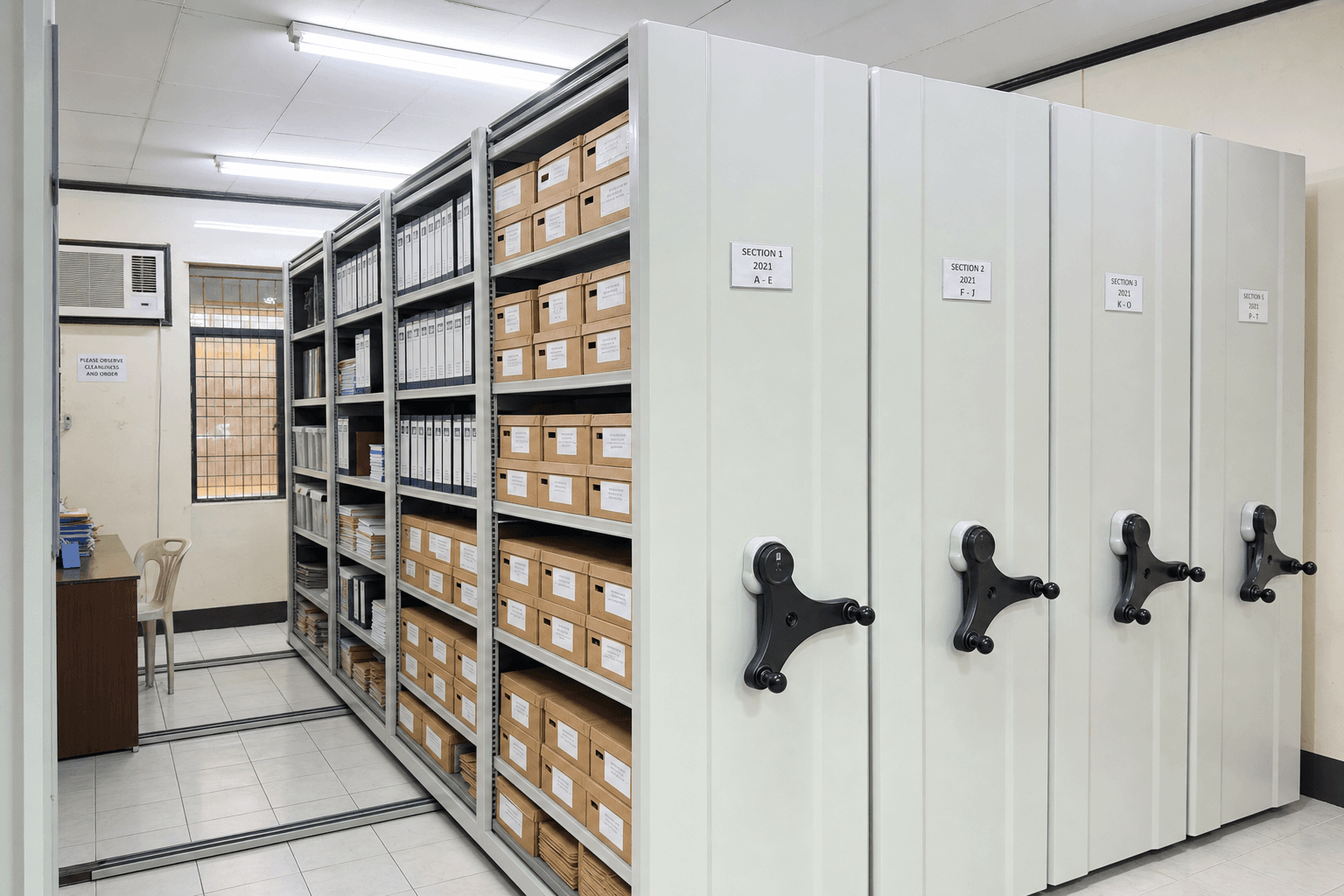 Mobile compactor shelving in a Philippine government archive room with documents and boxes